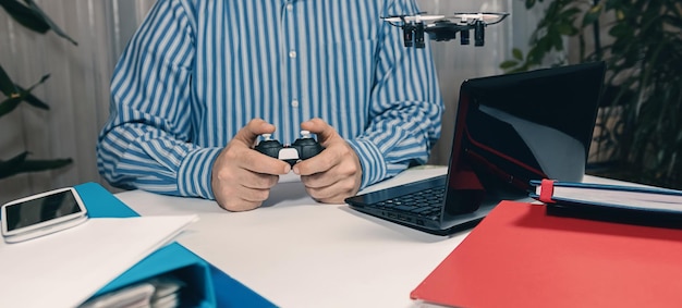A person writing a game review on their laptop, surrounded by gaming consoles, controllers, and game boxes. The scene suggests a passionate gamer immersed in the process of analyzing and documenting their gaming experience.
