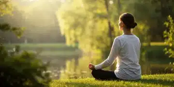 Pessoa meditando tranquilamente em um jardim verde, com a luz do sol filtrando pelas árvores, simbolizando paz interior e serenidade.