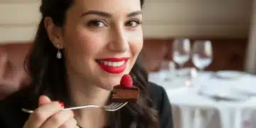 Woman with long-lasting red lipstick eating confidently